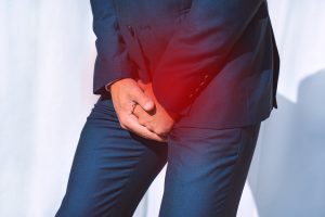 Homem com as mãos na região genital, para falar sobre o que é a hiperplasia prostática benigna